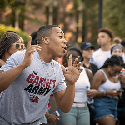 A student smiling and shouting at an event with other students.