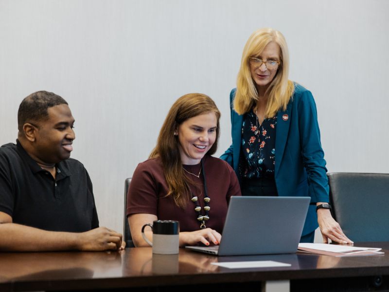 Employees reviewing content on laptop.
