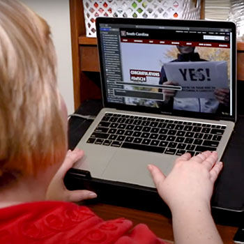 Person sitting at a desk typing on laptop computer.