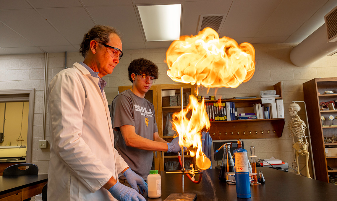 Student and professor conduct science experiment with fire.