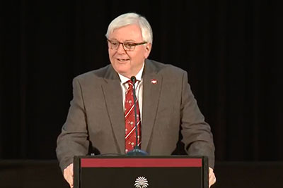 President Michael Amiridis standing at a podium delivering the State of the University address. 