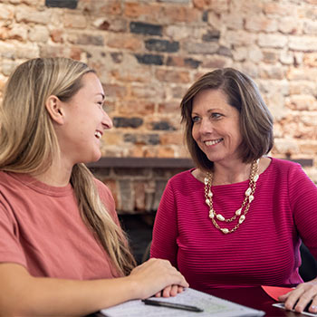 Student having a converstion sitting at a table with a professor. 