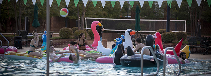 The outdoor pool at the fitness center at dusk with people hanging out getting ready to watch a movie at the Dive-In Movie event. 