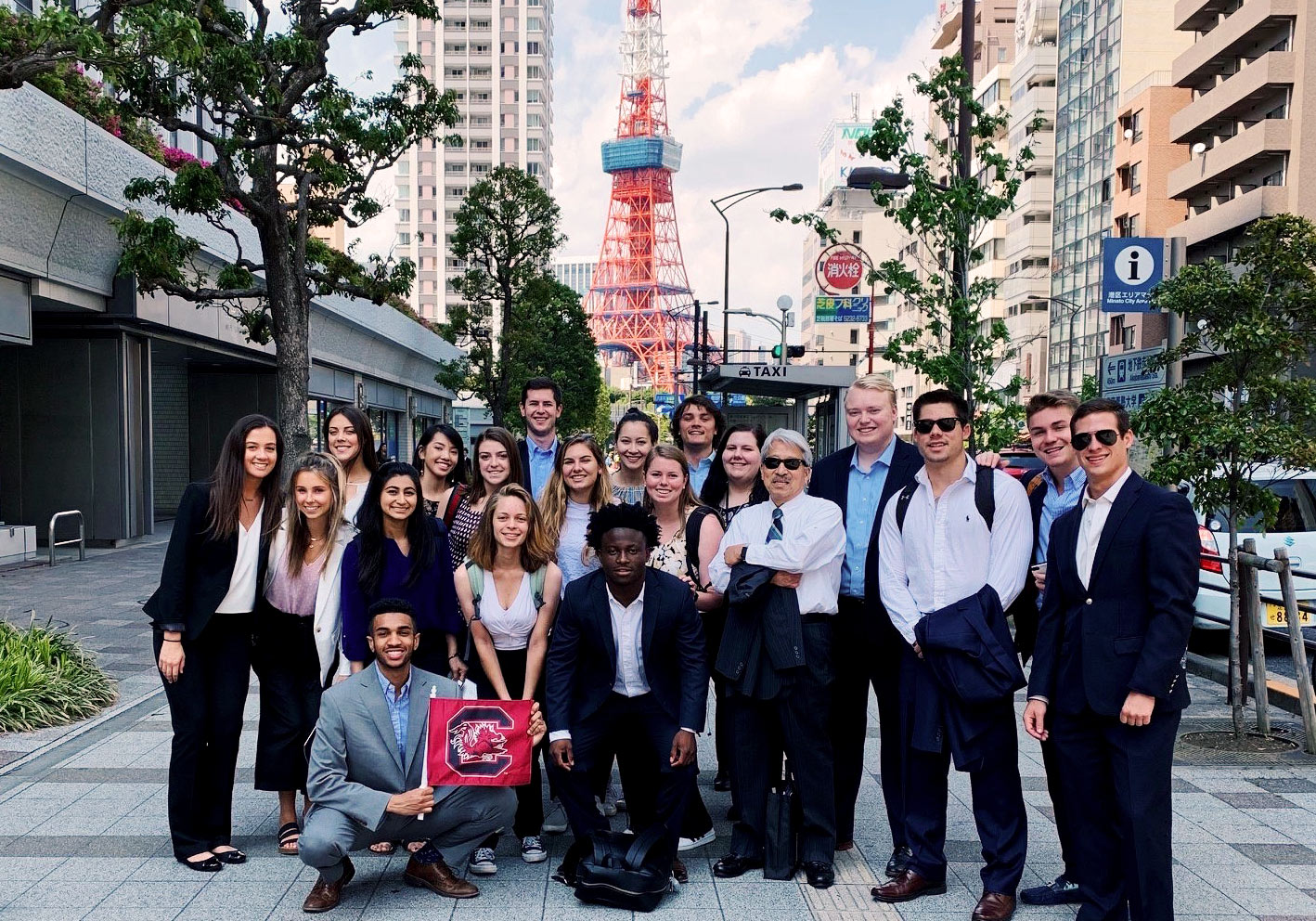 A group of students standing on the street in Japan holding a Gamecock flag. 