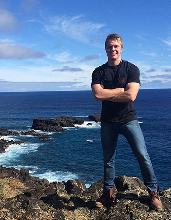 Student standing on a cliff overlooking the ocean.