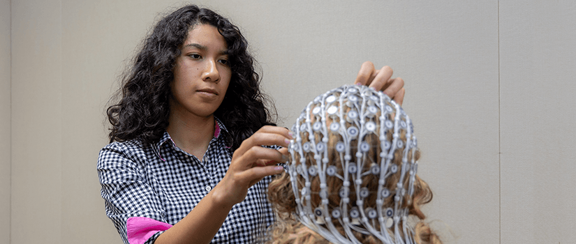 student adjusting electrode cap in a neuroscience lab