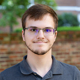 Photo of a man with dark hair and a  standing outside 