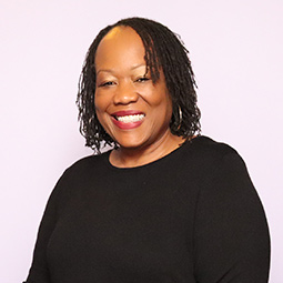 a photo of a woman with dark hair and black sweater on smiling