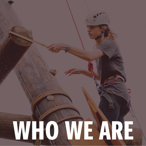 Female honors student measuring the UofSC climbing tower while wearing climbing gear and helmet