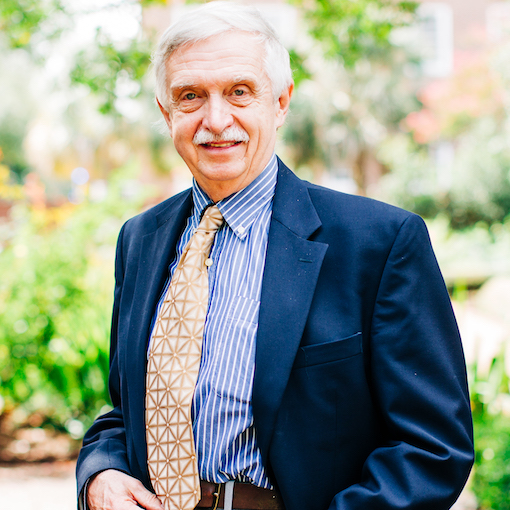 Dr. Herbert standing in front of a gate on the horseshoe