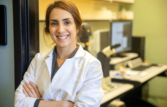 Student standing in lab smiling