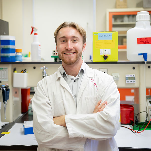 man in a white coat stands in a lab
