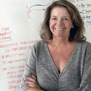 laura lanni stands in front of a white board with chemical formulas on it