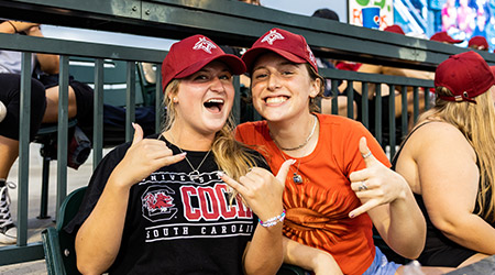 Two girls at USC Night at the Fireflies smiling and doing a spurs up.