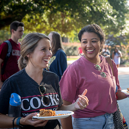 Two girls smiling and eating outside.