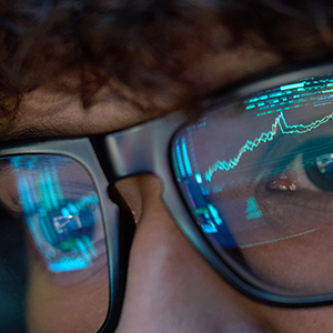 Data from a computer screen is reflected in the eyeglasses of a researcher.