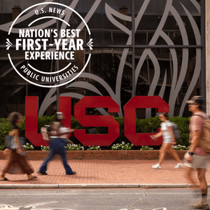 University of South Carolina (USC) students walk past a large USC logo outside a campus building. A graphic reads, “U.S. News Nation’s Best First-Year Experience — Public Universities.”