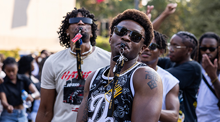 Two men wearing sunglasses with whistles outside.