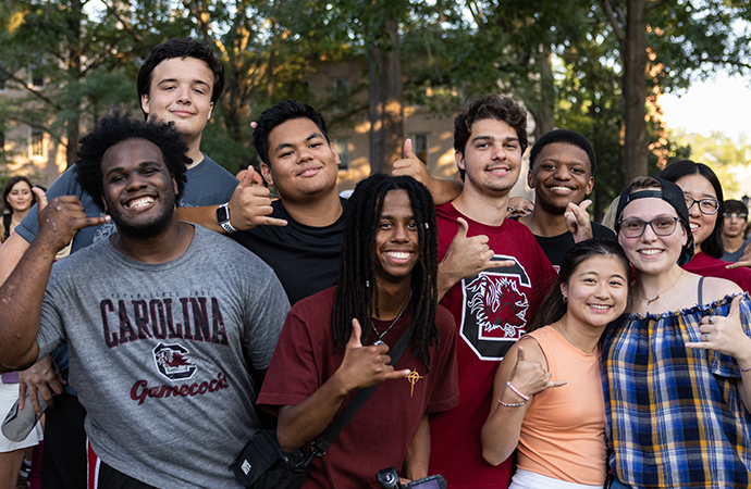 A group of eight students smiling on the Horseshoe at First Night Carolina.